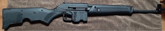 Kel-Tec SUB-2000 carbine with black stock and receiver, resting on a brown textured surface
