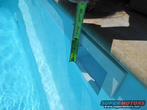 Measuring tape extended into a swimming pool, showing depth