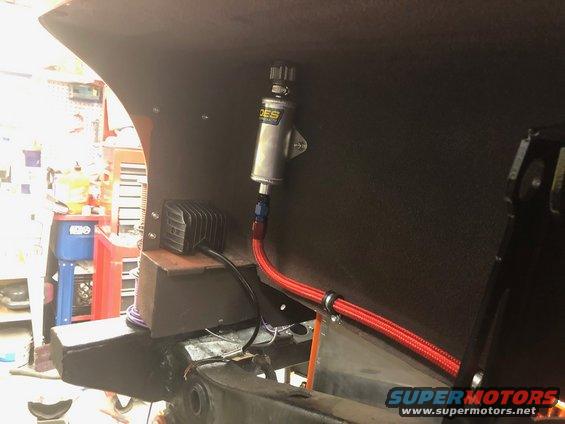 Fuel filter assembly with braided red line and a small black box mounted on a dark panel