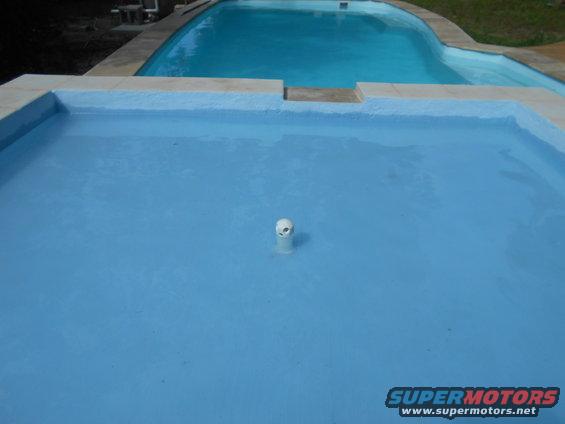 Swimming pool with a white pipe in the foreground and a larger pool in the background