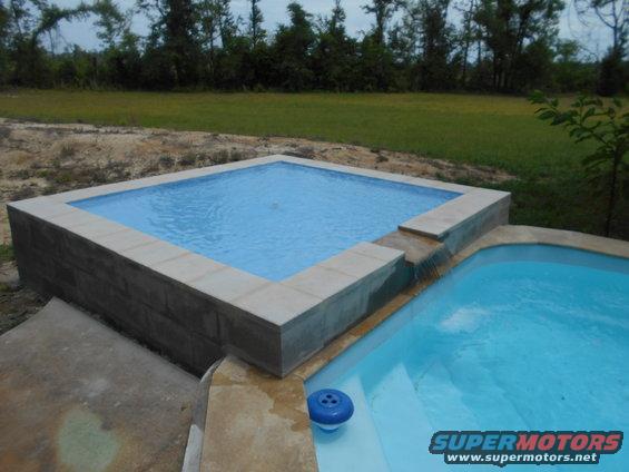 two swimming pools, one square and raised, the other kidney-shaped with steps