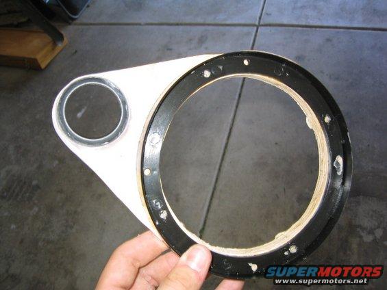 Hand holding a white and black speaker mounting adapter with two circular openings