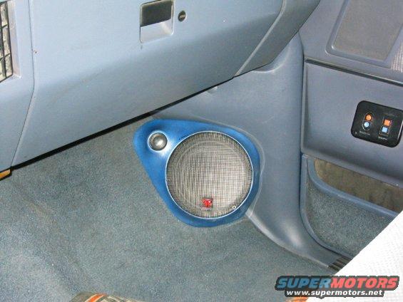 Blue-trimmed speaker mounted on gray carpeted interior panel