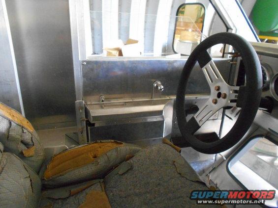 Interior of a vehicle with worn seats and a metal dashboard with a steering wheel.