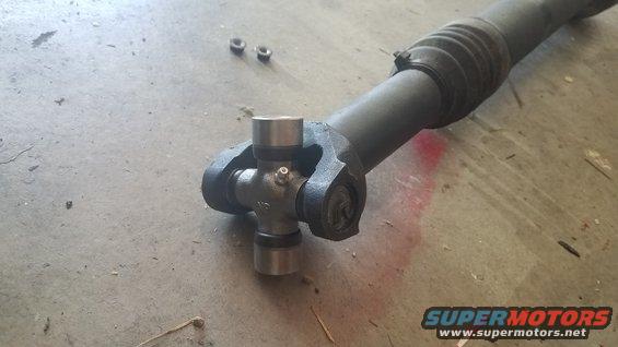 Close-up of a driveshaft U-joint with two nuts nearby