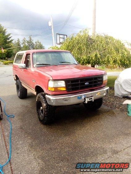 Red Ford Bronco with a white top, lifted, with aftermarket bumper and winch