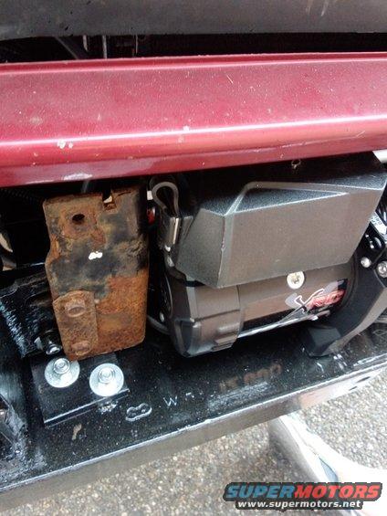 Winch and rusty mounting bracket attached to a vehicle frame