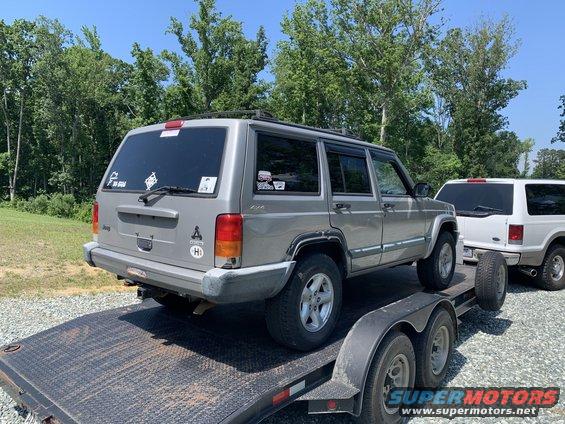 Silver Jeep Cherokee on a trailer, another SUV behind it