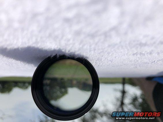 Car interior with fuzzy headliner and a circular reflection showing a body of water and trees