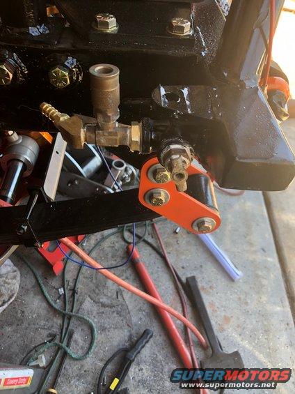 Orange suspension bracket attached to black frame with brass fittings and wiring