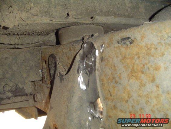 Close-up of rusted vehicle frame with visible welds and a rubber bushing
