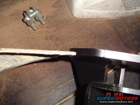 Metal bracket with bolts and a U-bolt clamp on a wooden surface