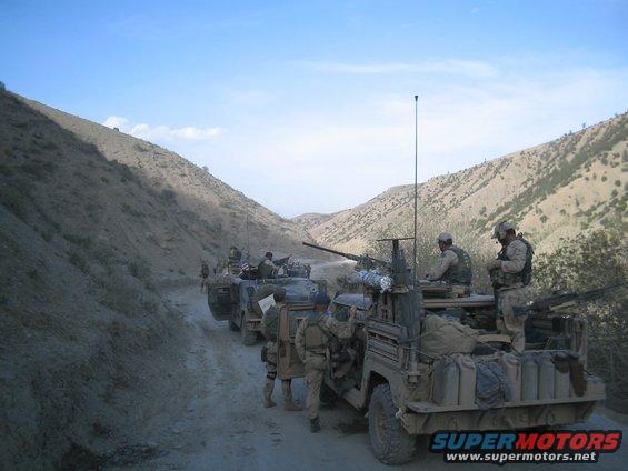 Military convoy on a dirt road with soldiers and vehicles