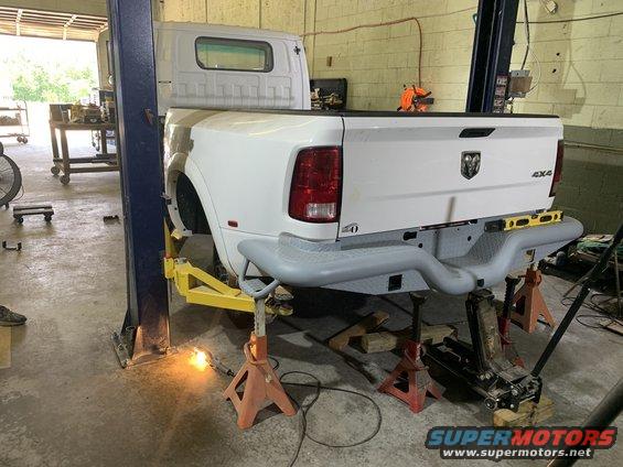 White pickup truck on a lift, rear view. Ram logo and 4x4 badging visible