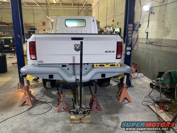 White pickup truck rear end with 4x4 badging, on jack stands in a garage