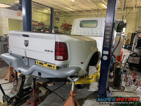 White pickup truck bed and cab on a lift, showing the rear bumper and 4x4 badging