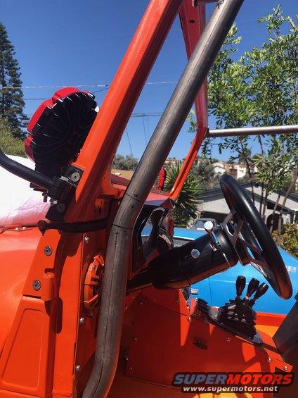 Orange off-road vehicle interior with roll cage, aftermarket steering wheel, and shifter