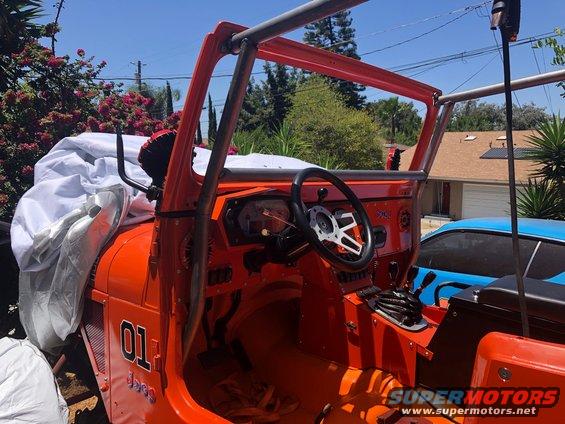 Orange Jeep interior with roll cage and custom steering wheel