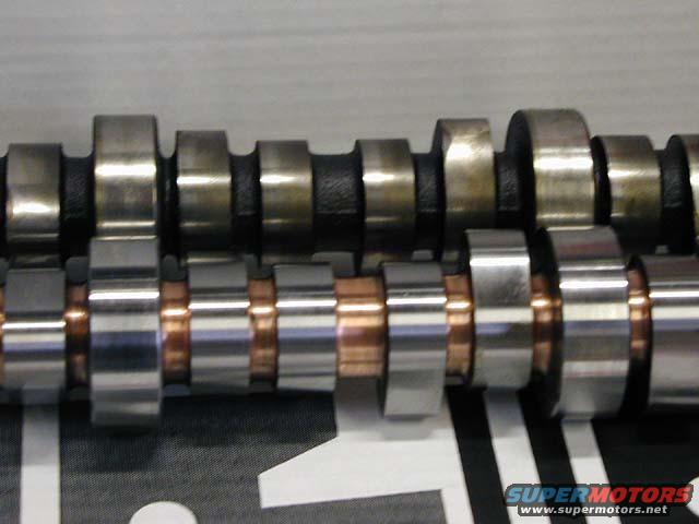 Two camshafts, one with black lobes and the other with copper-colored spacers