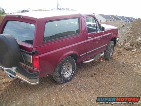 1994 Ford Bronco parked on a dirt road with construction in the background