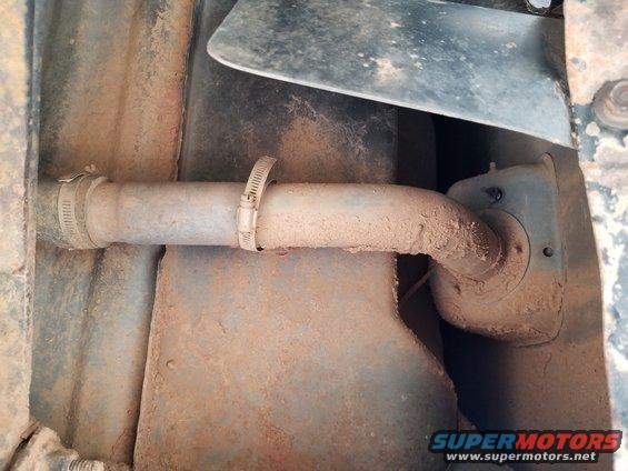 Undercarriage view of a rusty exhaust pipe with hose clamps, showing dirt and grime