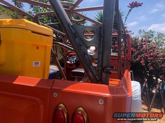 Orange vehicle's rear with a yellow cooler and custom roll cage. Steering wheel visible inside