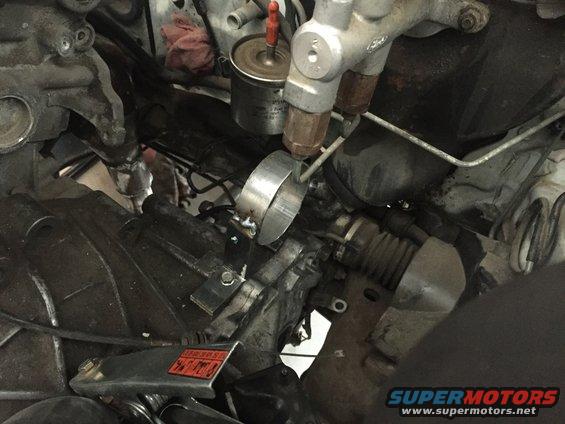 Close-up of engine bay with steering rack, brake lines, and fuel filter visible