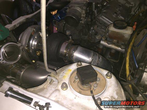 Engine bay with a turbocharger and intercooler piping installed. Brake fluid reservoir visible