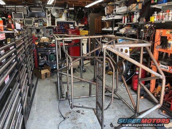 Bare metal custom roll cage frame in a garage workshop