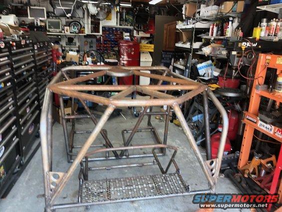 Custom roll cage frame in a garage with tool chests and equipment