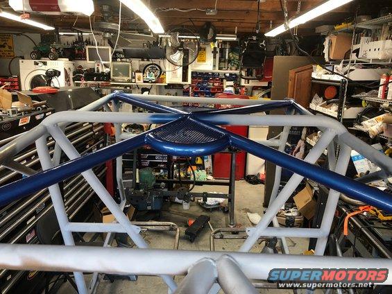 Roll cage structure with blue and white paint in a garage