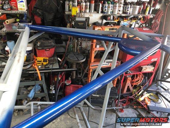 Blue and gray roll cage in a garage with tools and shelves