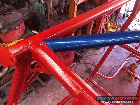 Close-up of a red and blue painted roll cage in a workshop
