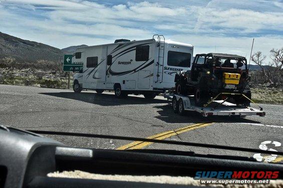 Black Jeep Wrangler on trailer, rear view, with yellow storage box