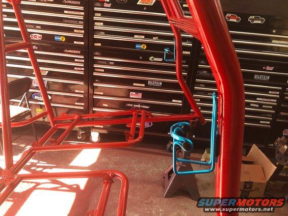Red roll cage with blue cup holder mounted on a jack stand