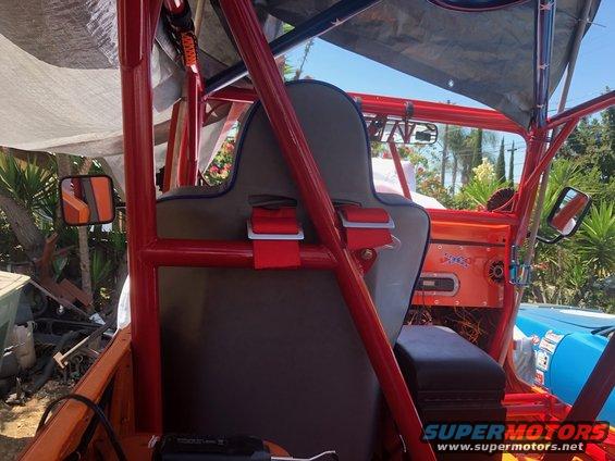 Interior view of a custom Jeep with red roll cage, racing seats, and aftermarket stereo. Visible text 'SUPERMOTORS'