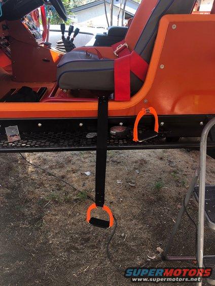 Orange Jeep interior showing seats, steering wheel, gear shifter, and orange grab handles with straps attached to the exterior