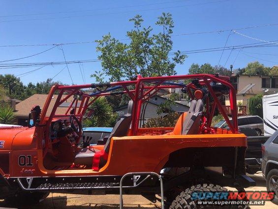 Orange Jeep CJ-7 with red roll cage, custom side steps, and '01 Jeep' text on door