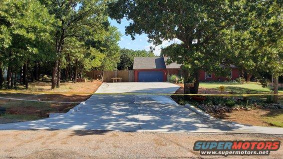 Newly poured concrete driveway in front of a house with a blue garage door