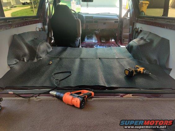 img_20200820_112033.jpg 20200820 - I started applying the new vinyl flooring I purchased from Bronco Graveyard (been sitting in the garage for over a year). The old beige carpeting was trashed. I kept the tailgate carpet, though, to match the trim around the sides and because the new flooring kit didn't come with a tailgate piece. Be aware of that if you buy from JBG. The gaps for the wheel wells in the bottom flooring are much bigger than the wheel wells. Hopefully the excess for the wheel wells will fill the gaps without looking too bad. Still gotta cut out the center where the rear seat locks in, and drill holes for the seat and seatbelt mounts. I used the heat gun to get the wrinkles out and, believe it or not, this looks way better than when I initially put it in. It's going to need a lot more massaging to get it flat before I start drilling and reinstalling things.