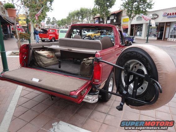 Red convertible SUV with spare tire on rear, tailgate down, interior cargo nets visible