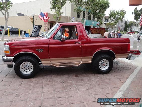 1994 Ford Bronco, red with tan trim, side view. Hood is open
