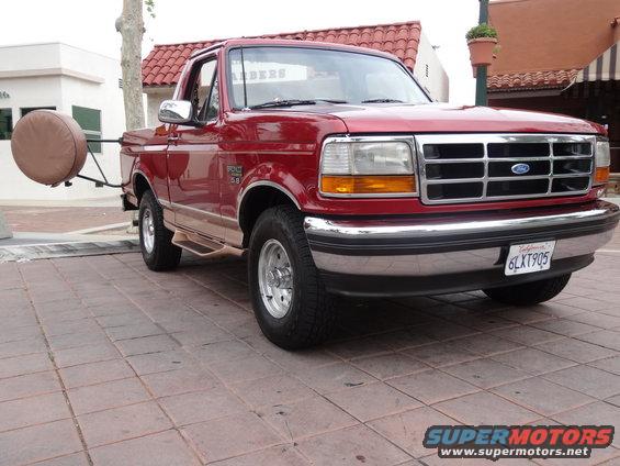 Red Ford F-150 pickup truck, 1992 model year, with a tan stripe and a spare tire carrier on the rear
