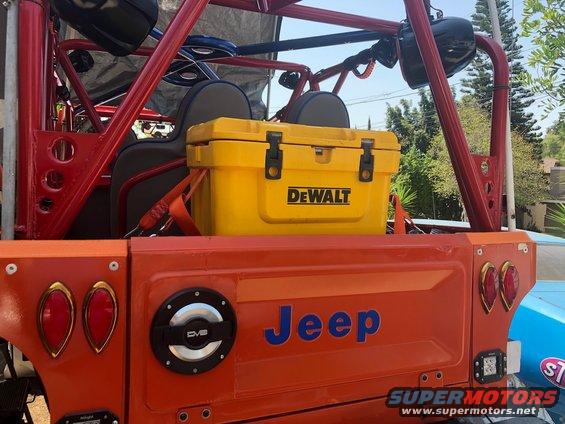 Orange Jeep tailgate with blue 'Jeep' lettering, yellow DeWalt cooler, and red roll cage