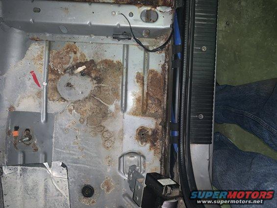 Rusted interior floor pan with visible structural damage