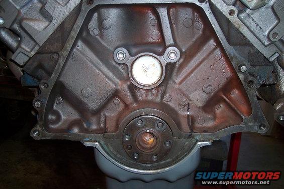 Rear seal area of an engine block, showing the crankshaft seal and mounting bolts. Supermotors.net logo visible