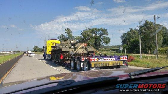 Tank on a flatbed trailer being transported on a highway