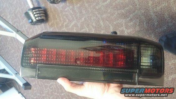 Darkened aftermarket tail light assembly held in hand