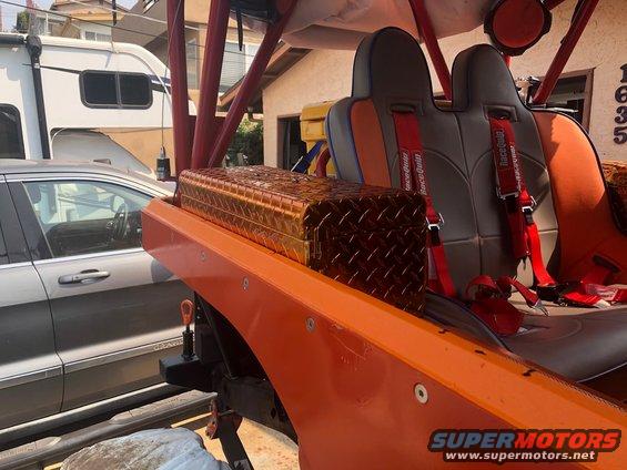 Orange Jeep interior with racing seats and diamond plate toolbox. Another vehicle and RV visible