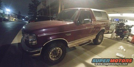 Maroon Ford Bronco with American flag decal on rear window, parked in garage